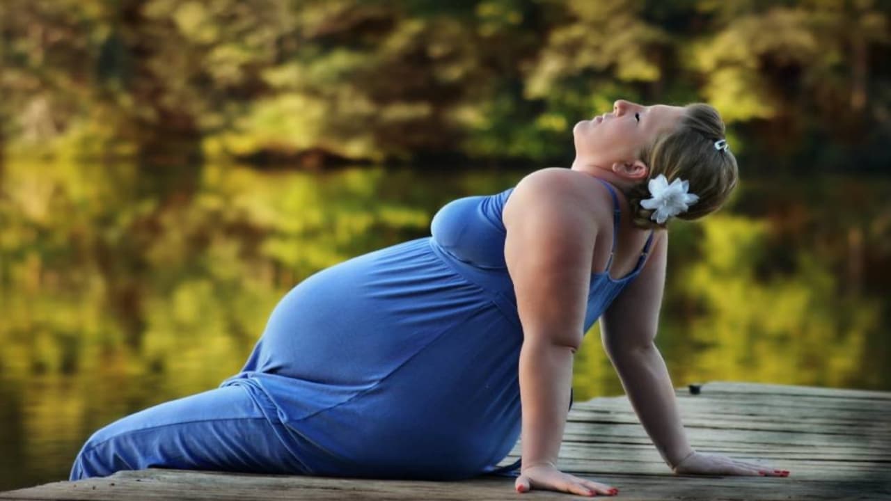 Mujer embarazada tomando el sol, pies en el agua